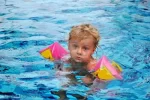 5288348-retrato-de-ni-a-con-manguitos-flotadores-inflables-en-la-piscina.webp